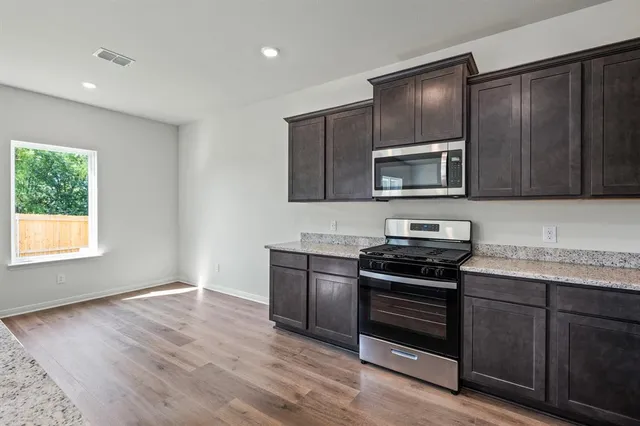 a kitchen with granite countertop wooden cabinets and stainless steel appliances