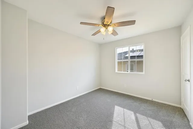 an empty room with windows and fan