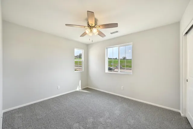 an empty room with windows and fan