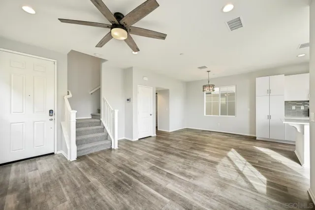 a view of a livingroom with wooden floor and ceiling fan