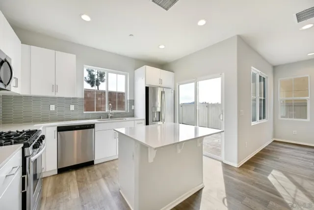 a large white kitchen with wooden floor and a sink