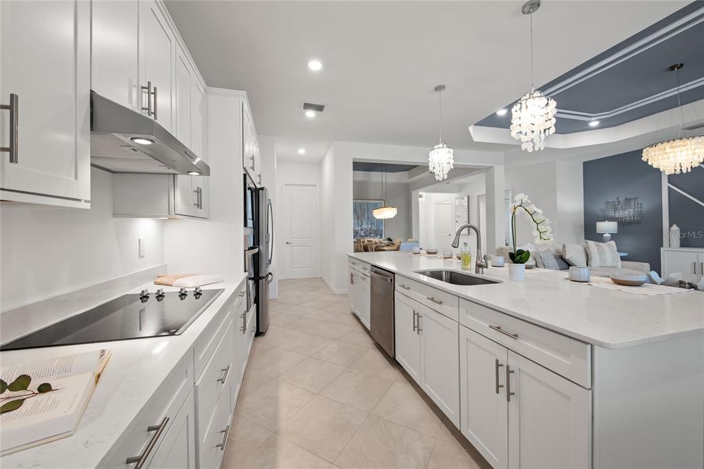 7161 Inlet Isles Lakewood Ranch, FL 34202 - Photo 12 of 29 a kitchen with a sink dishwasher a stove and white cabinets with wooden floor