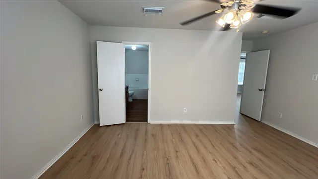 wooden floor in an empty room with a chandelier fan