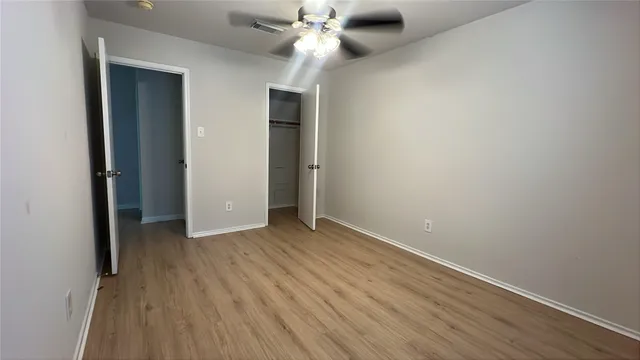 an empty room with wooden floor closet and windows