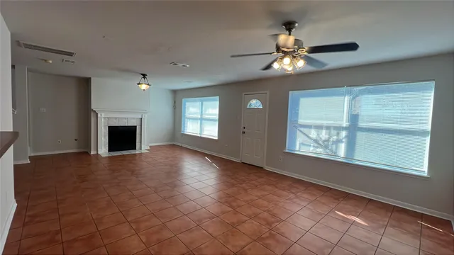 an empty room with windows and fireplace