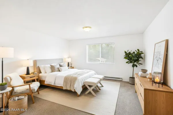 a bedroom with a bed table chair and a flat screen tv