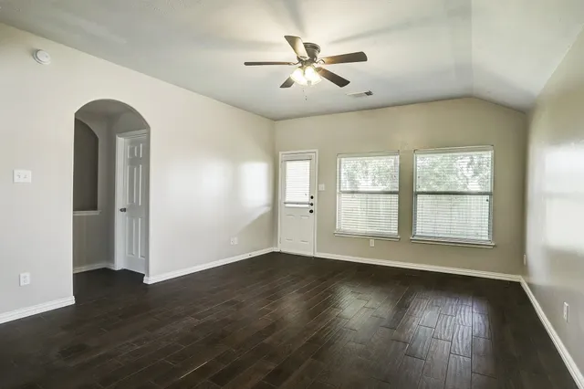 a view of an empty room with wooden floor and a window