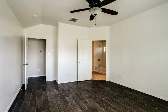 a view of a hallway with wooden floor and a ceiling fan