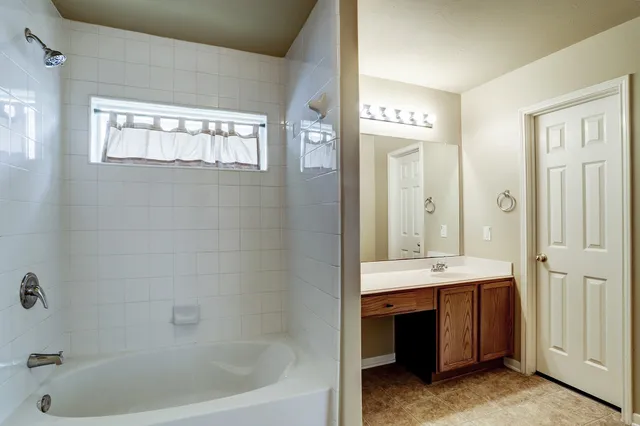 a bathroom with a tub a sink and a mirror
