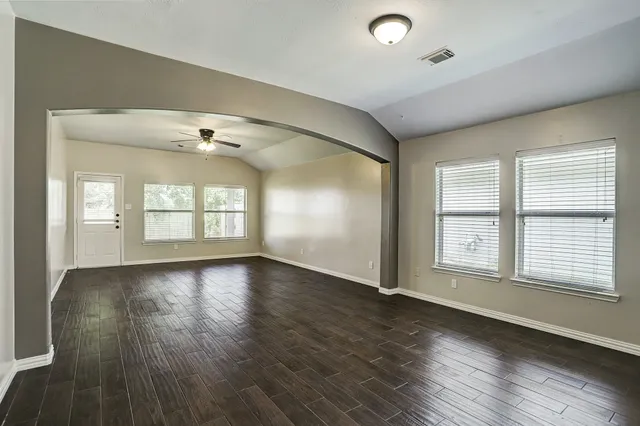 an empty room with wooden floor and windows