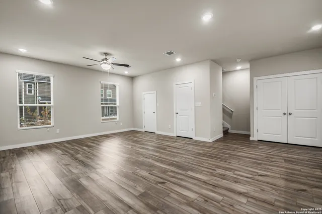a view of an empty room with wooden floor and windows