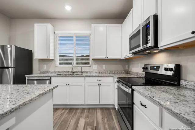 a kitchen with stainless steel appliances granite countertop a sink stove and microwave