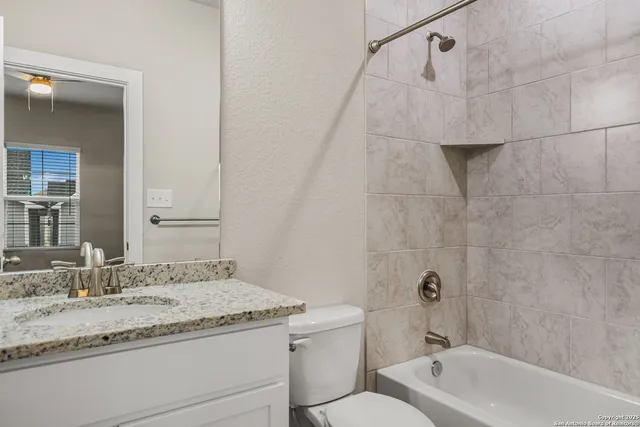 a bathroom with a granite countertop sink a toilet and bathtub