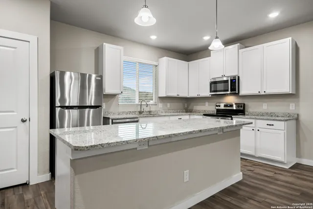 a kitchen with stainless steel appliances granite countertop a refrigerator a stove a sink and a microwave