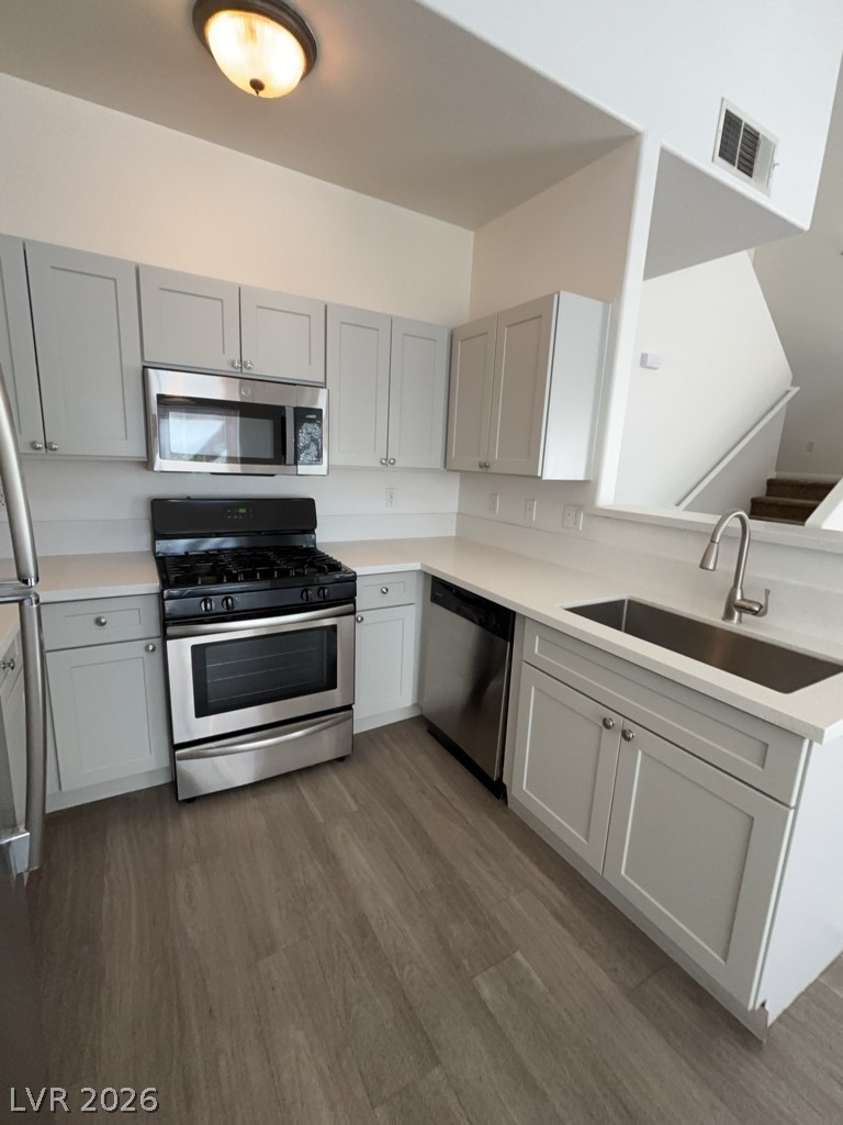 4915 East Russell Road, Unit 159 Las Vegas, NV 89120 - Photo 4 of 12 Kitchen featuring stainless steel appliances, dark wood-style flooring, a peninsula, and gray cabinetry