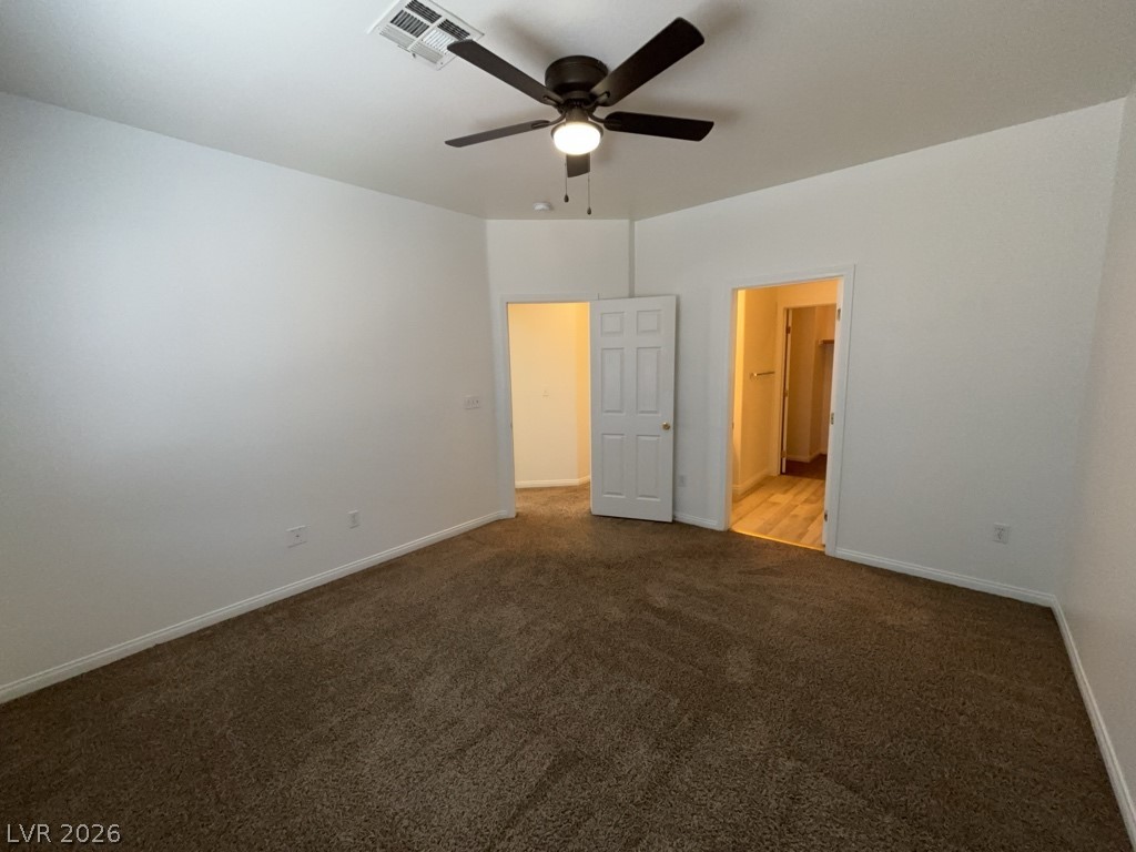 4915 East Russell Road, Unit 159 Las Vegas, NV 89120 - Photo 8 of 12 Unfurnished bedroom with a ceiling fan, dark carpet, and ensuite bath
