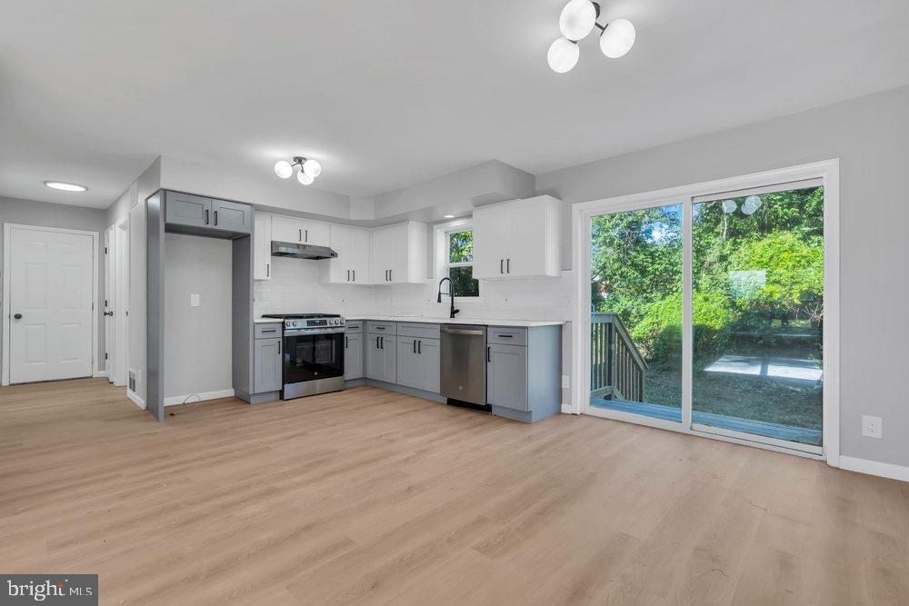 345 Spruce Street Bridgeton, NJ 08302 - Photo 27 of 43 a view of a kitchen with stainless steel appliances granite countertop a stove a sink dishwasher and white cabinets with wooden floor