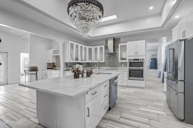 a kitchen with stainless steel appliances a table chairs in it and an empty room