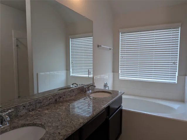a bathroom with a granite countertop sink and a window