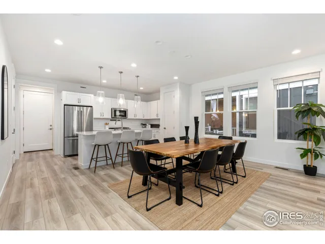 a open kitchen with stainless steel appliances kitchen island granite countertop a table chairs and a refrigerator