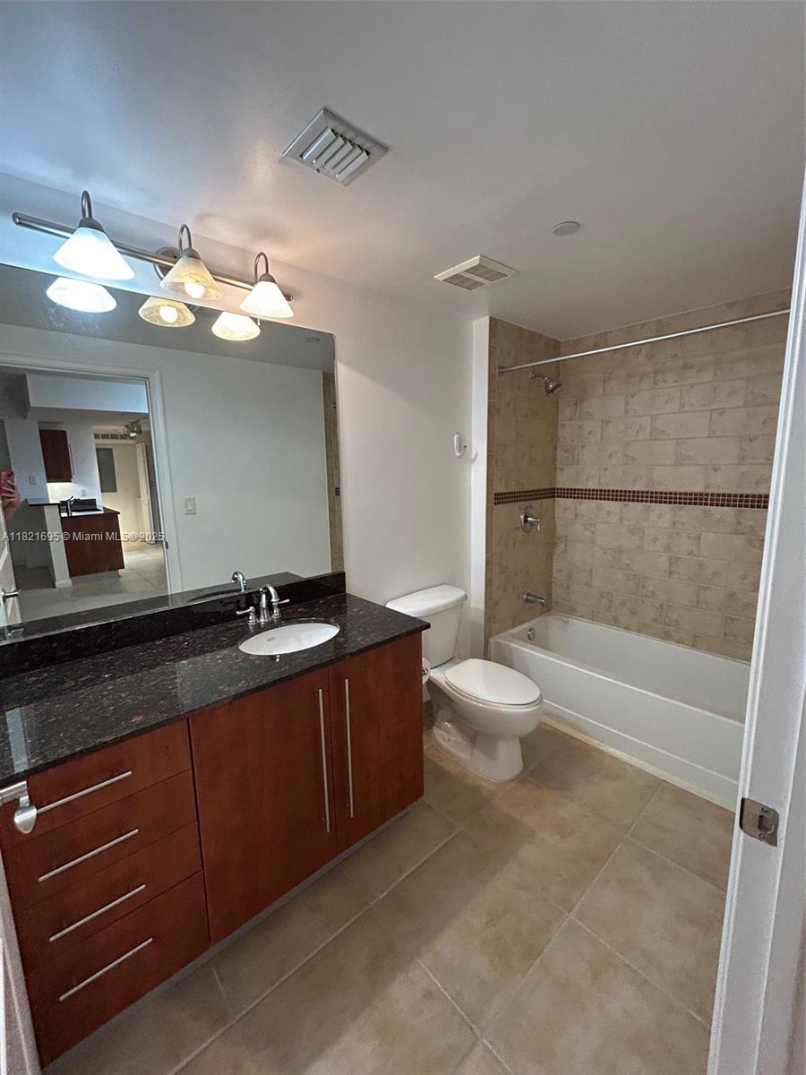 a bathroom with a granite countertop sink a toilet a mirror and bathtub