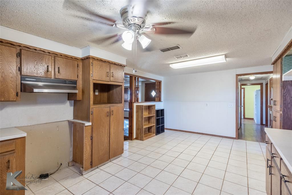 405 South Hinton Street Benjamin, TX 79505 - Photo 11 of 40 Kitchen with brown cabinetry, ceiling fan, a textured ceiling, light countertops, and light tile patterned floors