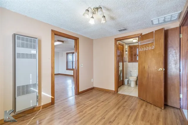 a view of a hallway with wooden floor and a bathroom