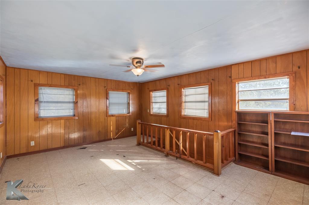 405 South Hinton Street Benjamin, TX 79505 - Photo 20 of 40 Empty room featuring light floors, wood walls, and ceiling fan