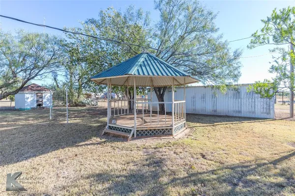 a backyard of a house with table and chairs under an umbrella