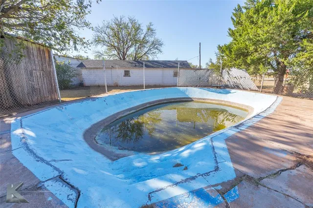 a view of a backyard with large trees and wooden fence