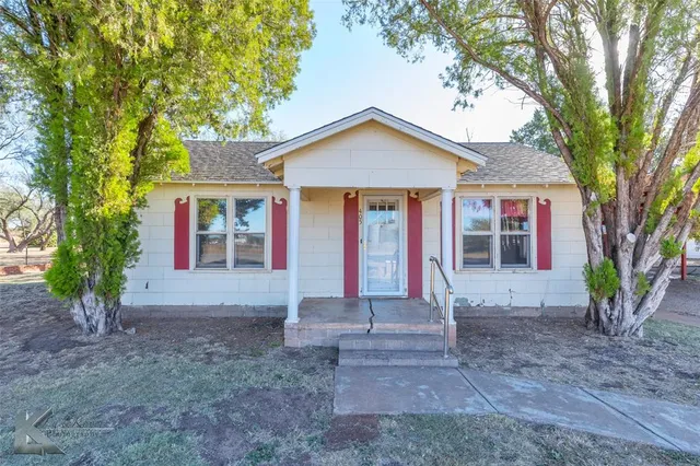 a view of a house with backyard and trees