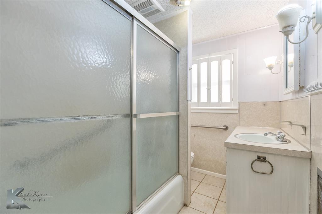405 South Hinton Street Benjamin, TX 79505 - Photo 7 of 40 Full bath featuring vanity, combined bath / shower with glass door, light tile patterned floors, and a textured ceiling