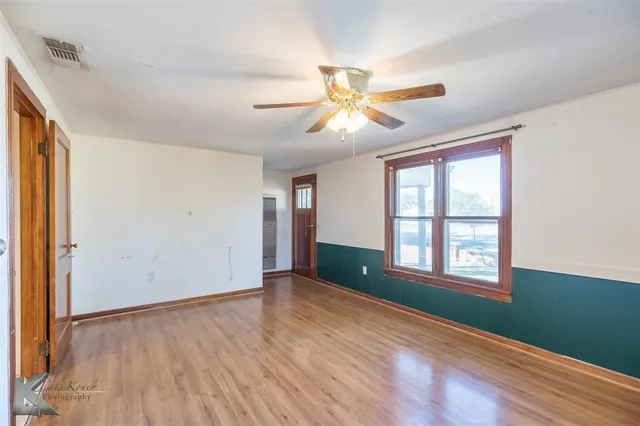 a view of an empty room with a window and wooden floor