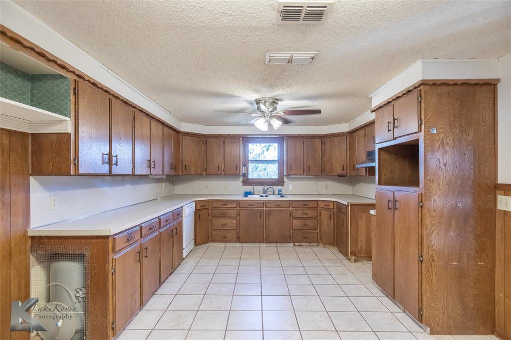 405 South Hinton Street Benjamin, TX 79505 - Photo 10 of 40 Kitchen with brown cabinetry, a textured ceiling, light tile patterned flooring, light countertops, and ceiling fan