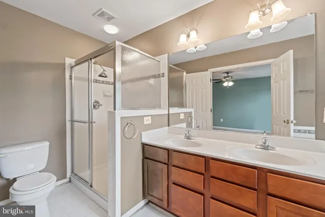 a bathroom with a shower sink vanity mirror and toilet