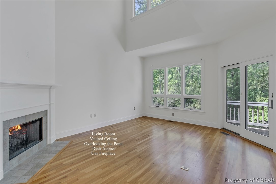 5818 Rivers Landing Terrace, Unit 5818 White Stone, VA 22578 - Photo 10 of 50 Unfurnished living room with plenty of natural light, a high ceiling, light hardwood / wood-style flooring, and a fireplace
