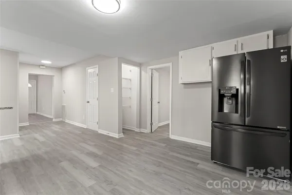 a view of an empty room with wooden floor and a refrigerator