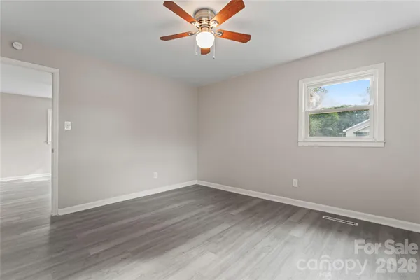 an empty room with wooden floor ceiling fan and windows