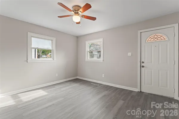 a view of an empty room with a window and wooden floor