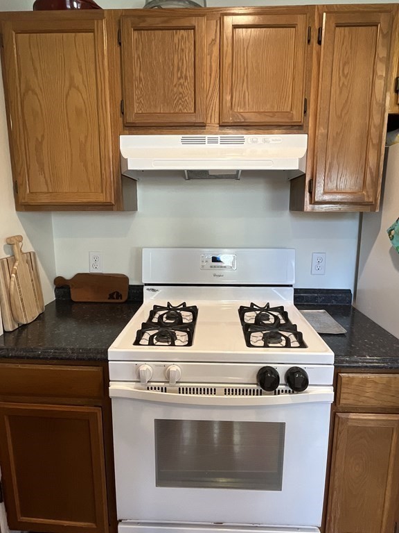 26-28 Normandy Road Auburndale, MA 02466 - Photo 10 of 31 a white stove top oven sitting inside of a kitchen with granite countertop wooden cabinets