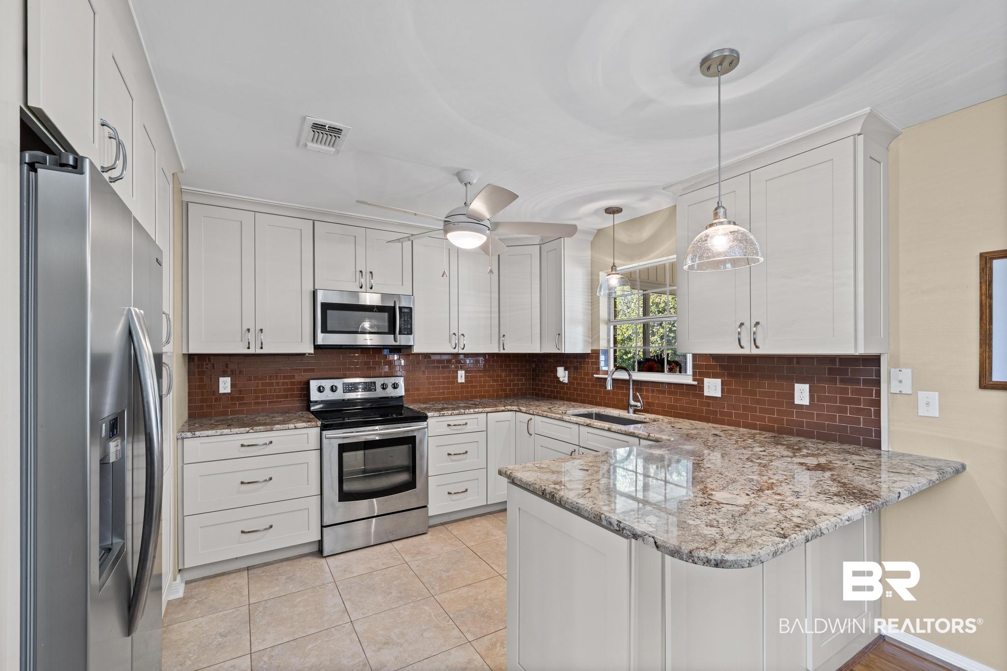 2881 Eslava Circle Lillian, AL 36549 - Photo 10 of 58 Kitchen featuring stainless steel appliances, a peninsula, white cabinetry, decorative light fixtures, and light tile patterned flooring
