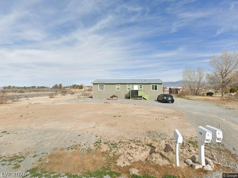 An inviting gravel driveway leads to a cozy residence set amidst a spacious, clear lot.