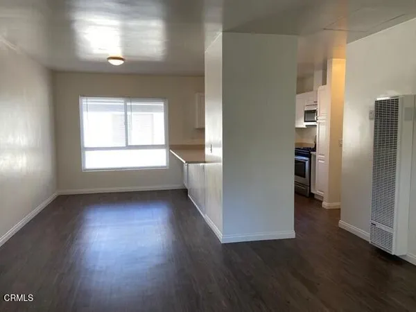 a view of an empty room with wooden floor and a window