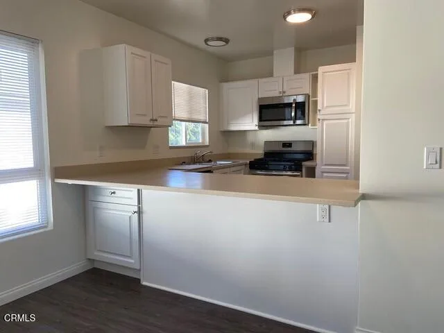 a kitchen with stainless steel appliances a sink a stove a microwave and cabinets