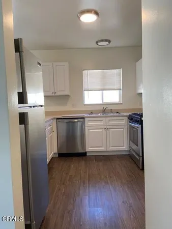 a kitchen with stainless steel appliances a sink cabinets and wooden floor