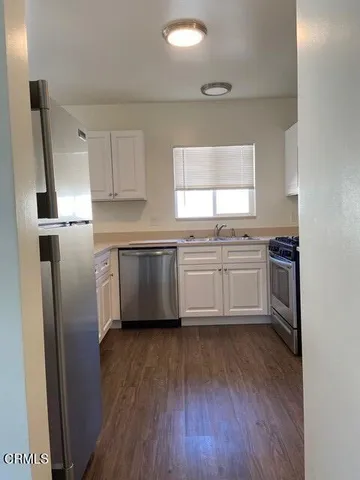 a kitchen with stainless steel appliances a sink cabinets and wooden floor
