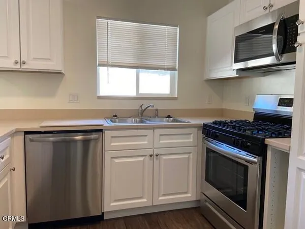 a kitchen with granite countertop cabinets stainless steel appliances and wooden floor