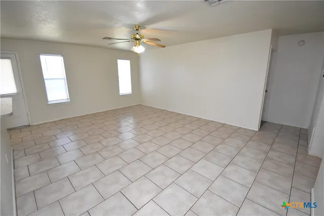 an empty room with windows and chandelier fan