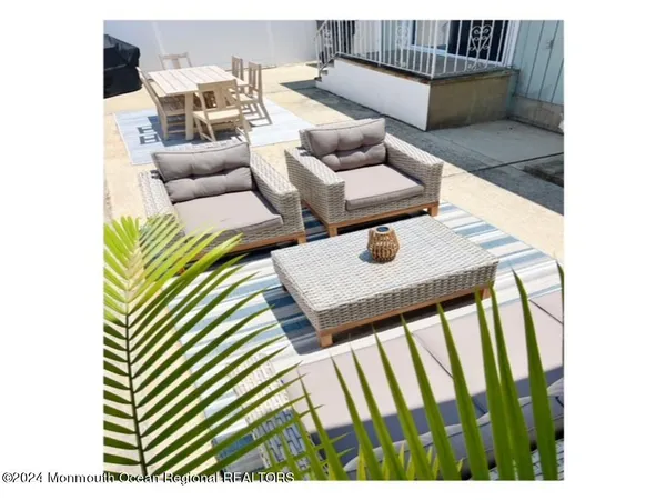 a view of a patio with table and chairs under an umbrella with a barbeque grill