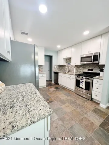 a kitchen with stainless steel appliances granite countertop a stove top oven a sink and a refrigerator